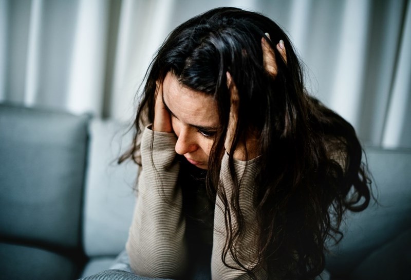 Brown haired woman holding her face with her hands.
