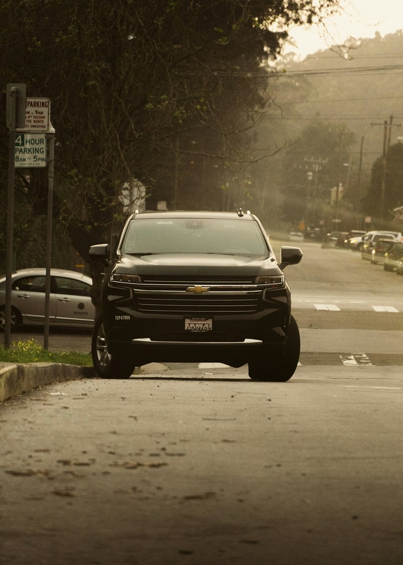 Neighbor driving a black SUV, turning into a new homeowner's lawn to park his car.
