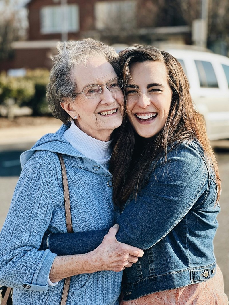 Old woman and adult woman hugging each other smiling in the street.
