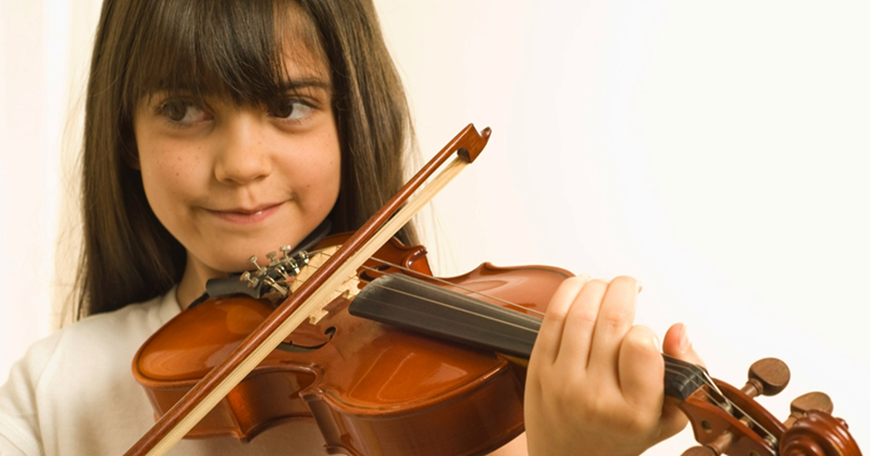 Close-up of a young girl playing the violin against a white background