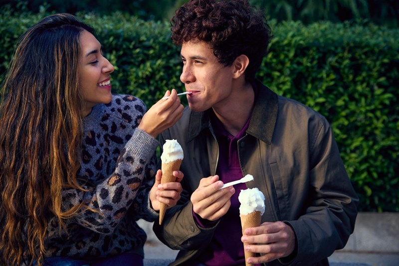 Man and woman eat ice cream together while on a date.