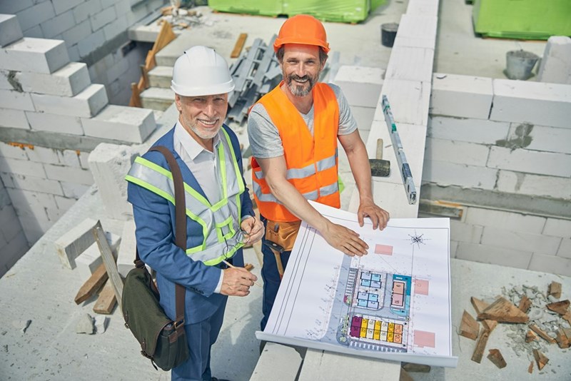 Construction duo look at building plans together.