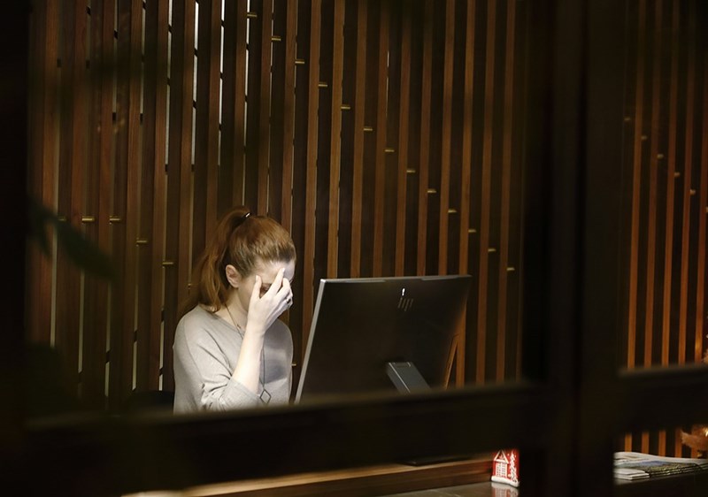 A burned out woman sits in front of a laptop