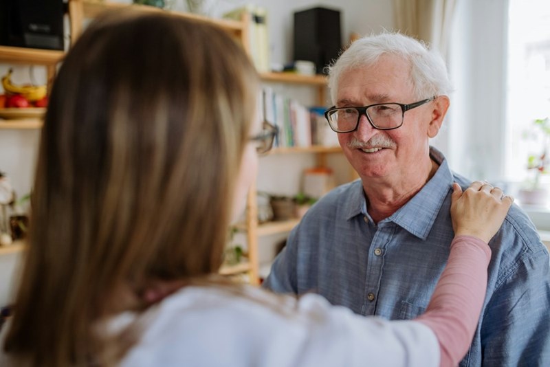 A grandfather shares a warm, meaningful moment with his granddaughter at home.