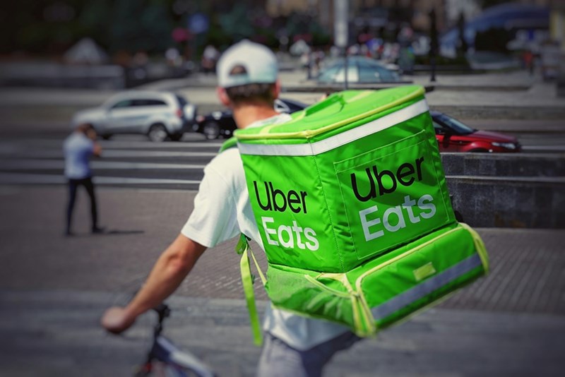 An Uber Eats delivery driver rides a bicycle.