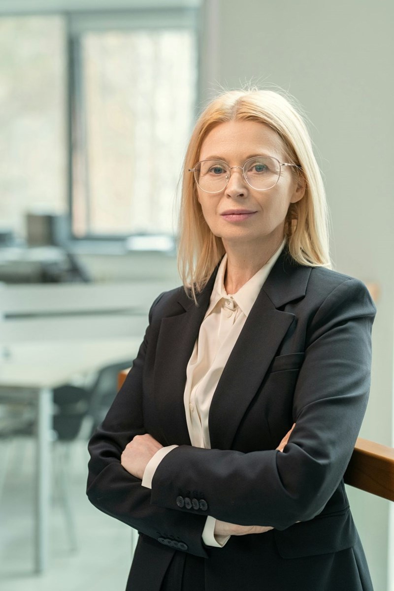 Portrait of content confident female business executive in black jacket crossing arms on chest