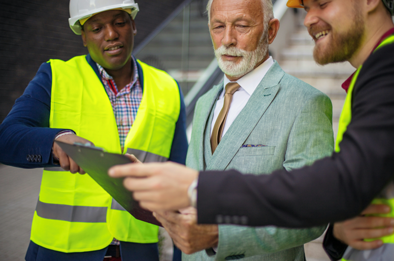 Construction workers and a boss in a suit discuss plans.
