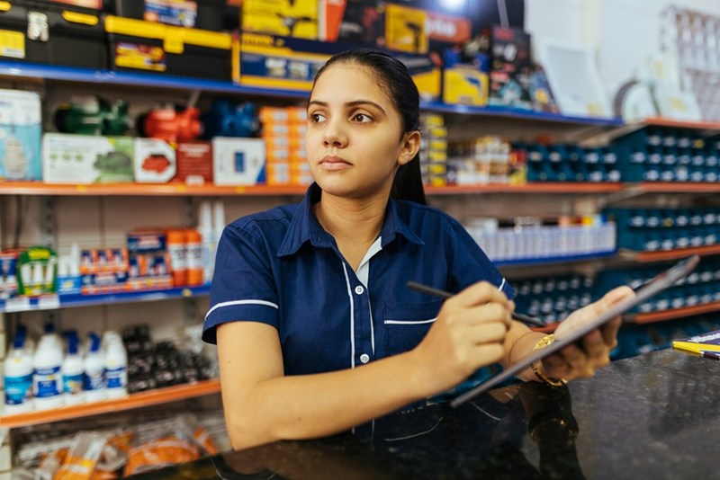 A convenience store worker stands at the cashier