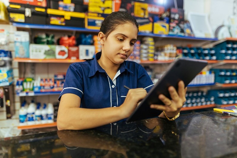 A young convenience store worker writes on a clipboard