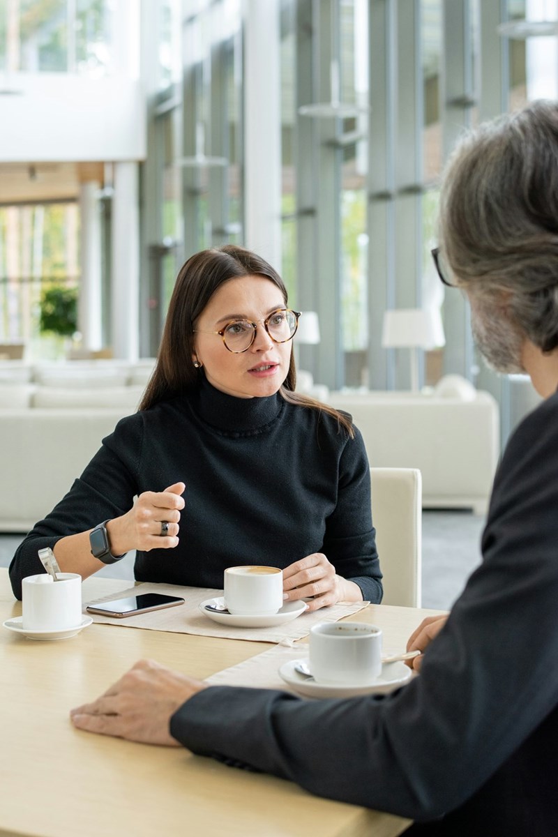A professional woman with glasses talking serious shop at work