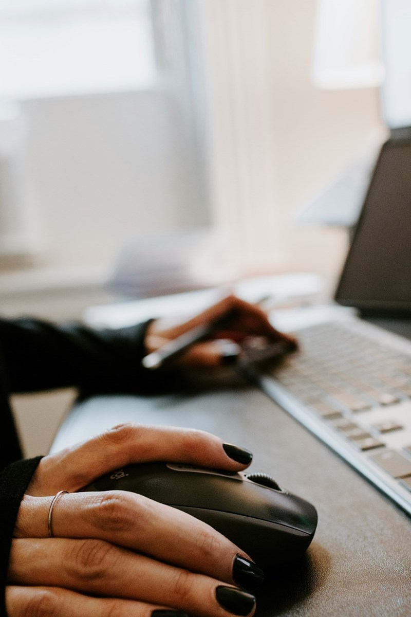 Painted nails and ringed fingers type and use the mouse of a computer.
