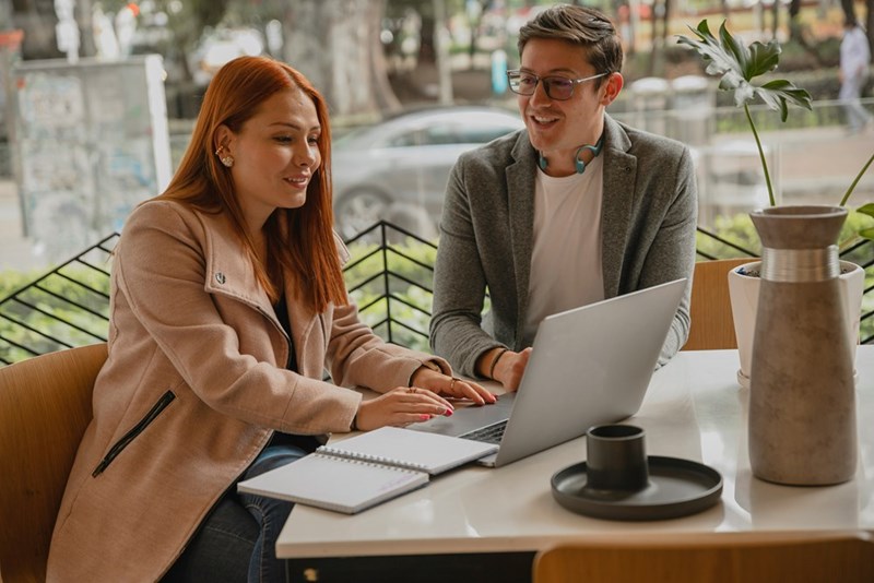 A project manager reviews a software platform with a team member on the laptop.