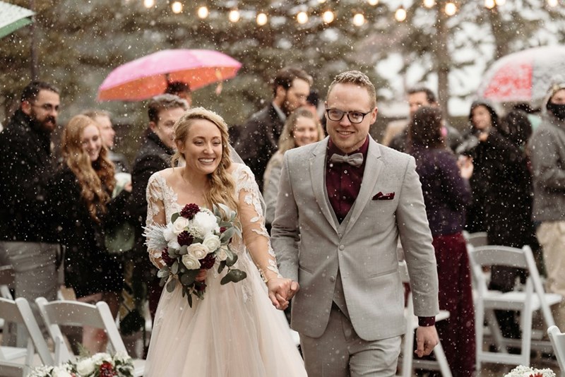 Newlyweds walk down the aisle while it rains.