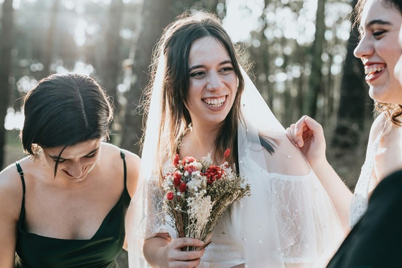 A bride smiles among her bridesmaids as she holds a bouquet of flowers