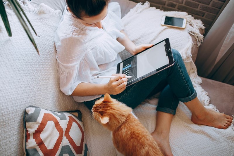Employee works from home while her cat keeps her company.