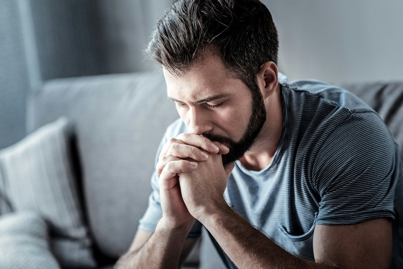A man looks upset with his head in his hands