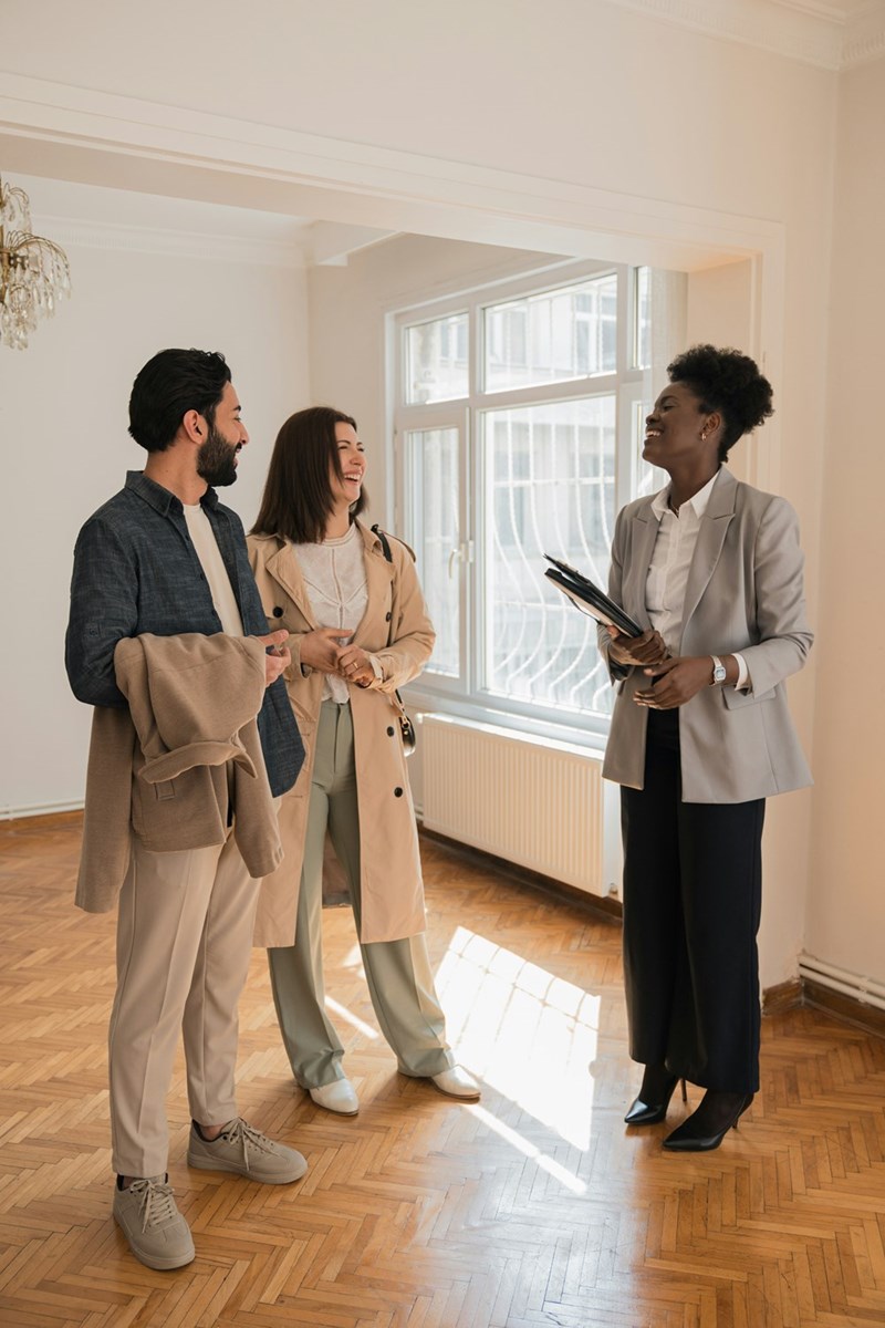 Couple being shown the inside of a house for sale by a happy real estate agent