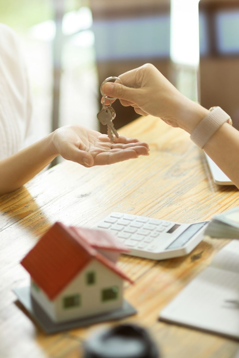 Real estate agent handing over the keys to a recently purchased house to a homebuyer