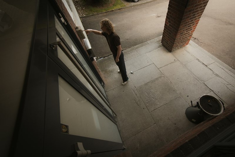 Fish eye angle of a woman knocking on house's front door.