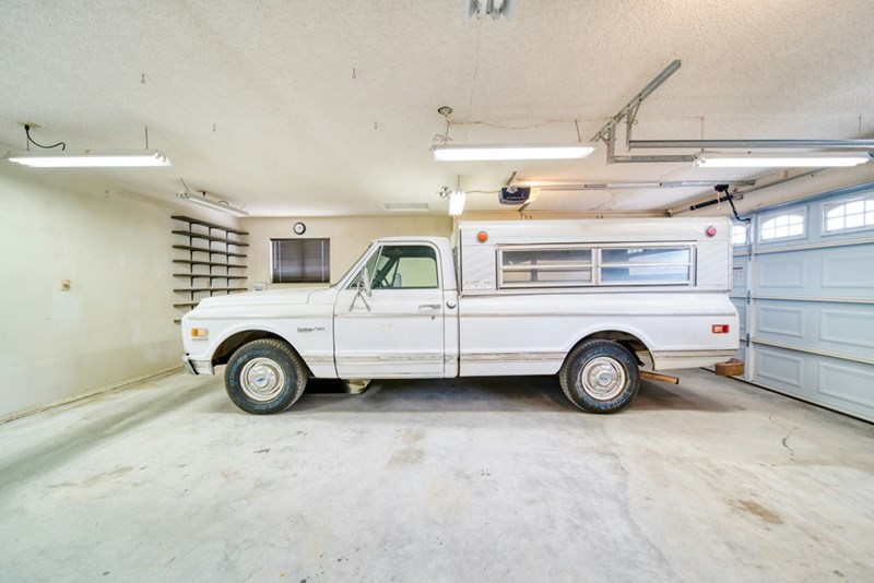 A white pick-up truck parked in a large garage with white led lights.