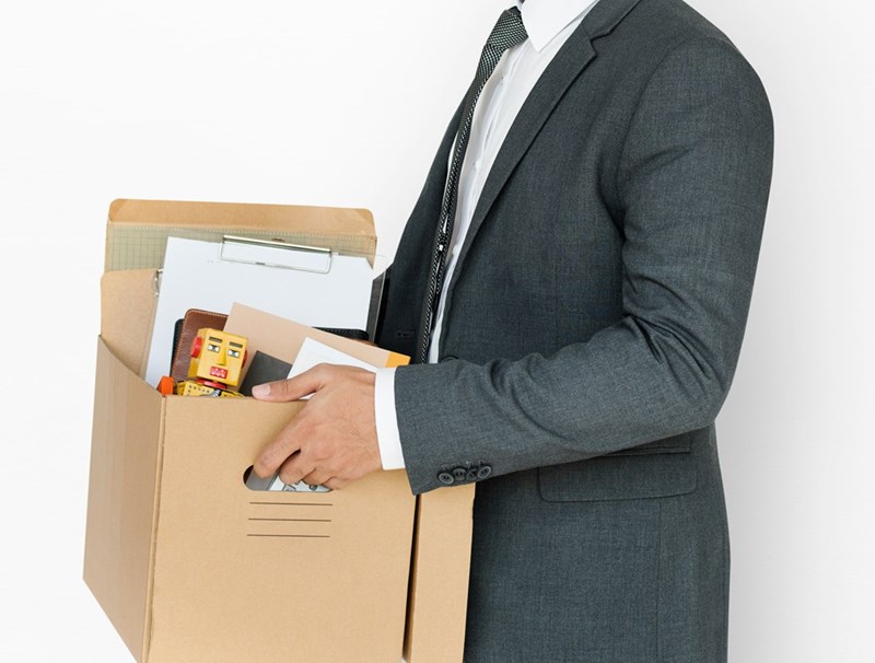 A businessman holds a cardboard box of personal items.