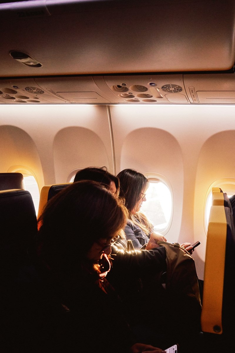A family sits inside an airplane as the setting sun shines in.