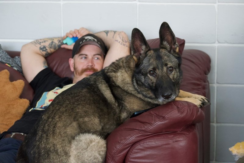 A man lying on the couch with his dog.