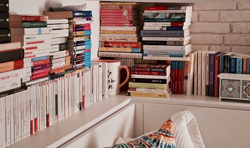 A bookshelf filled with lots of books on top of a white shelf