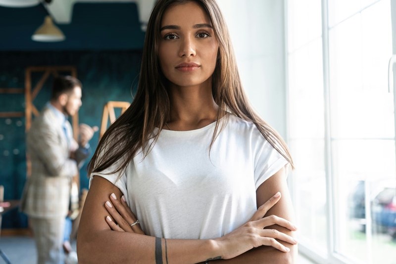 Worker crosses arms after hearing coworkers say mean things about her.