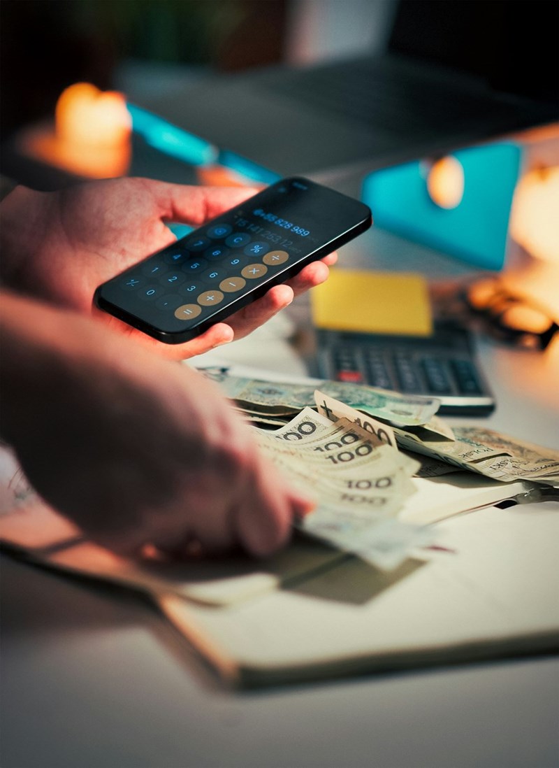 Hands holding money and using the calculator.