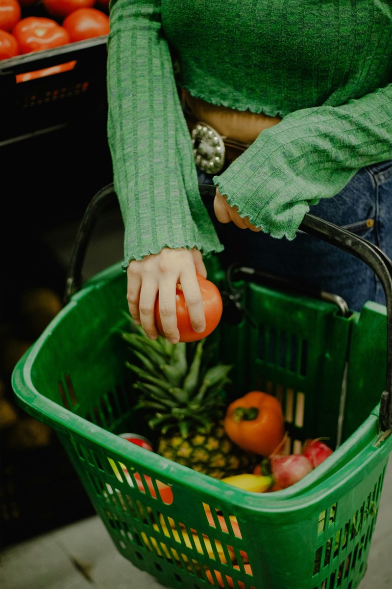 Shopper places a tomato in her basket.