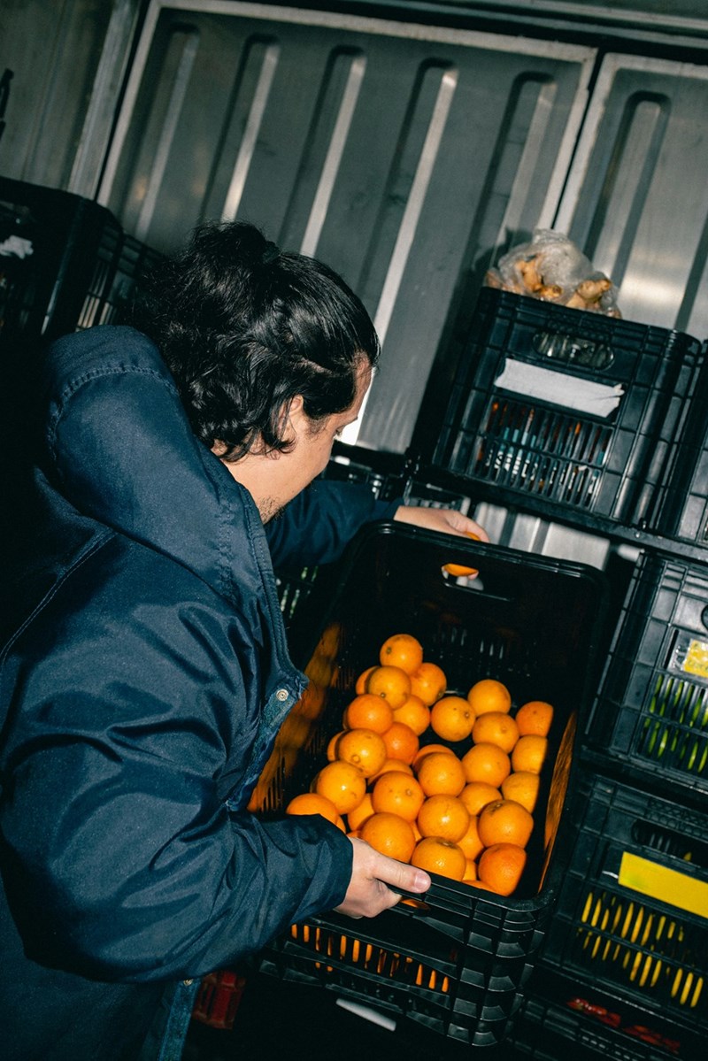 Grocery worker stocks oranges in an industrial fridge.