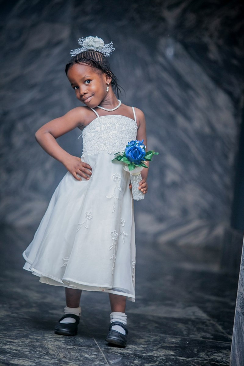 A young girl in a white dress holding a blue rose