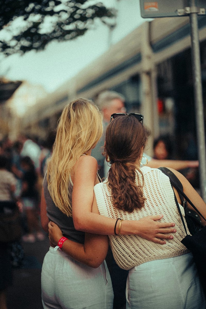 Two friends hugging each other looking at the people infant of them.
