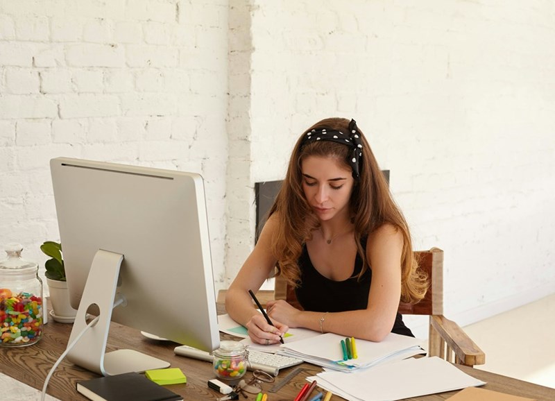 Young employee writes at her desk.