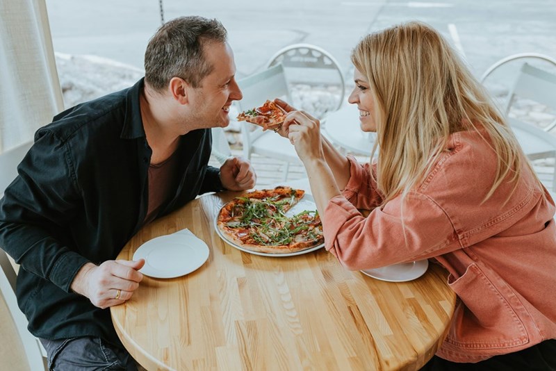 Woman gives her date a bite of pizza.