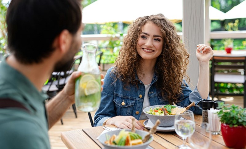 Woman listens to her date with amusement while they dine together.