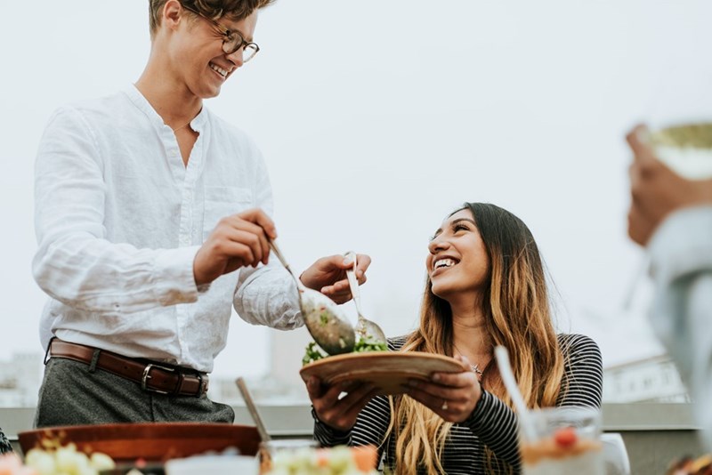 Man serves a woman salad.