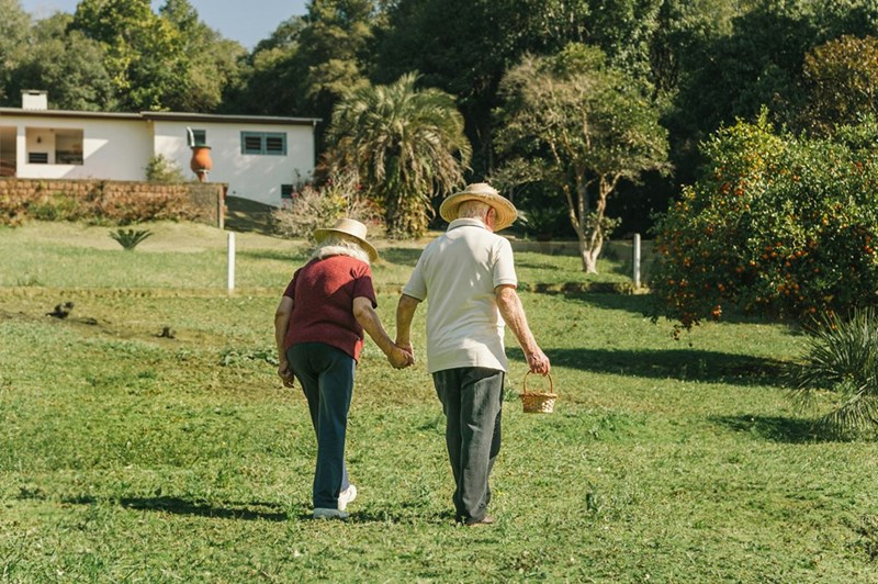 A couple of people walking across a lush green field