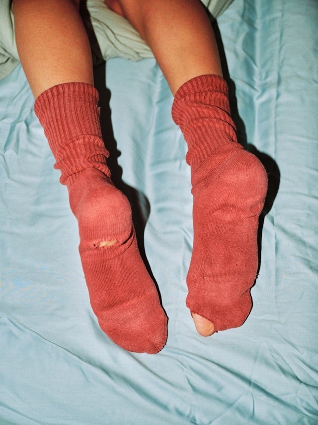 Pair of worn red socks with holes on blue sheets