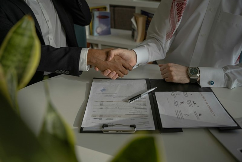 Two people shake hands over a piece of paper