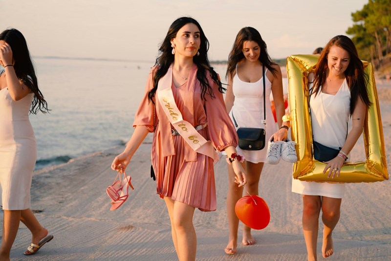 Bridal party walk along the beach during bachelorette party.