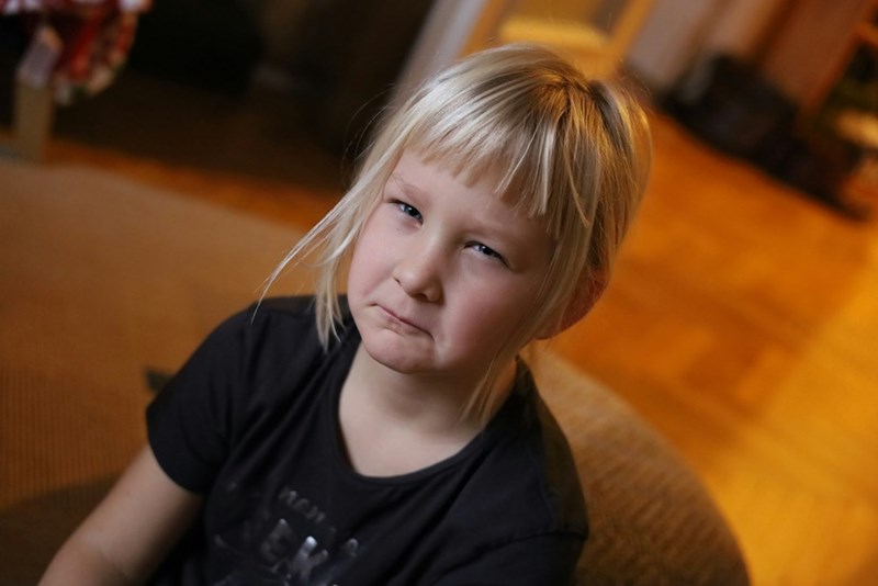 A little girl sitting on a couch looking at the camera