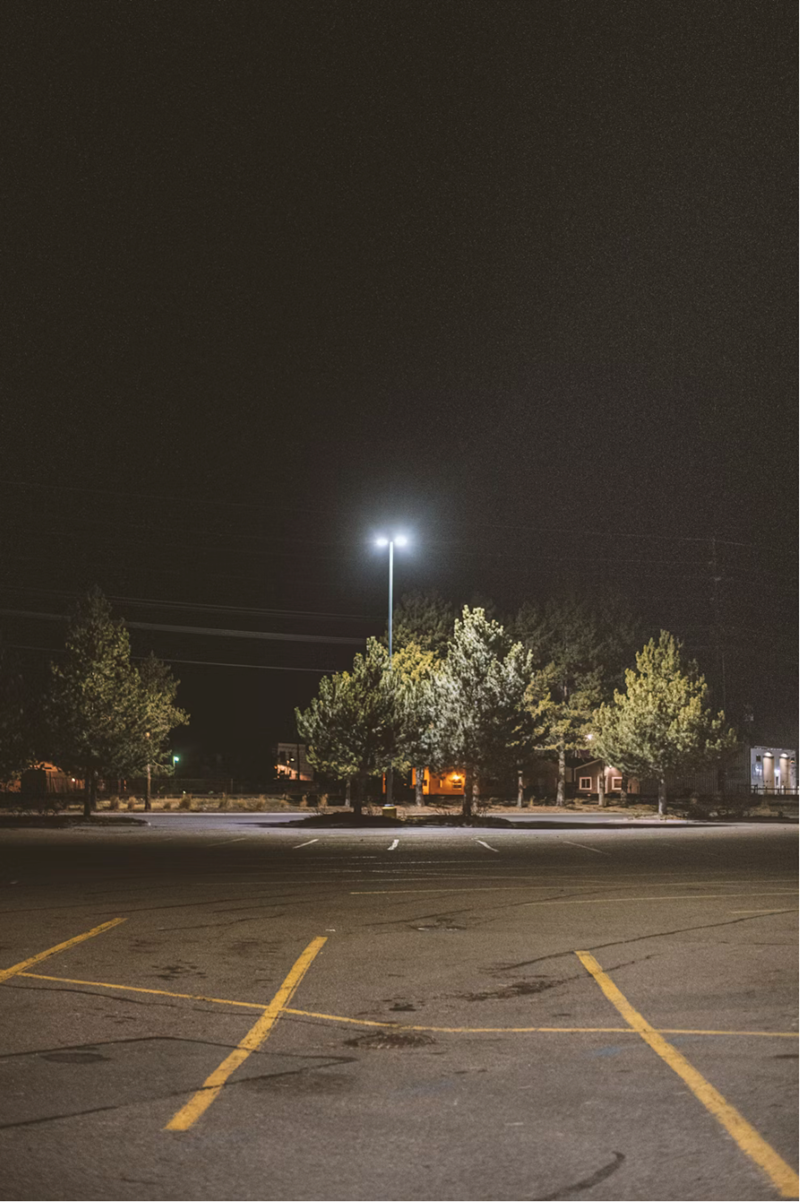 An empty parking lot at night with white lights.