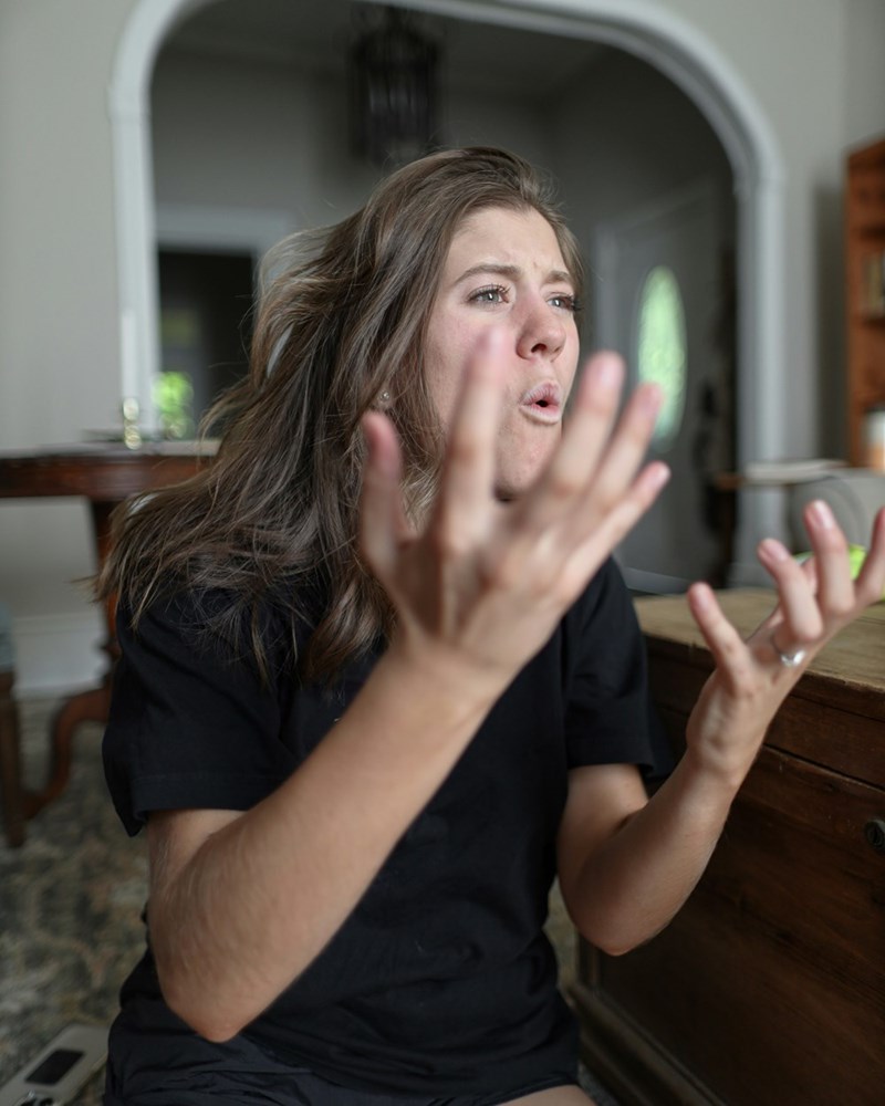 A woman sitting on the floor with her hands in the air