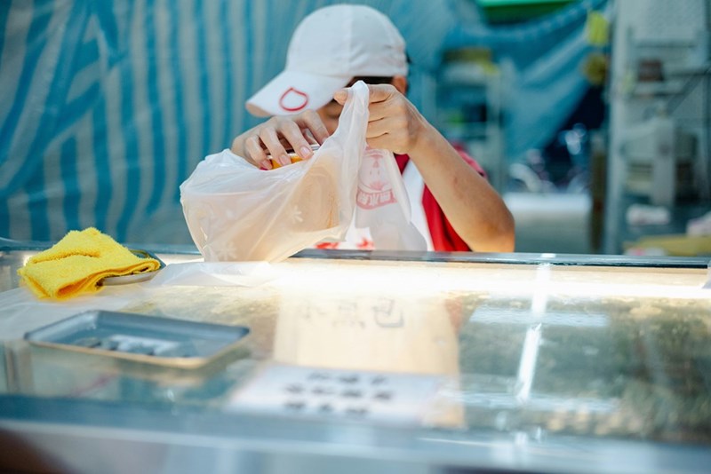 A food vendor packs goods in a plastic bag