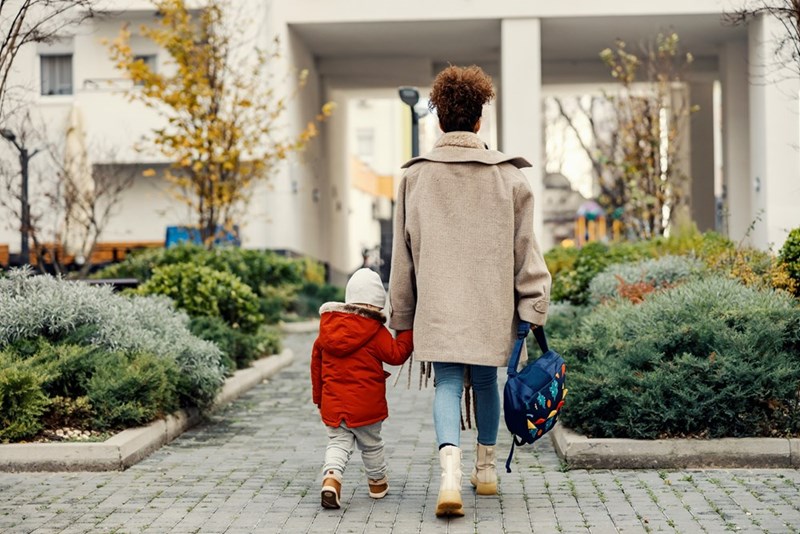 A mother and her young child walk hand in hand outside