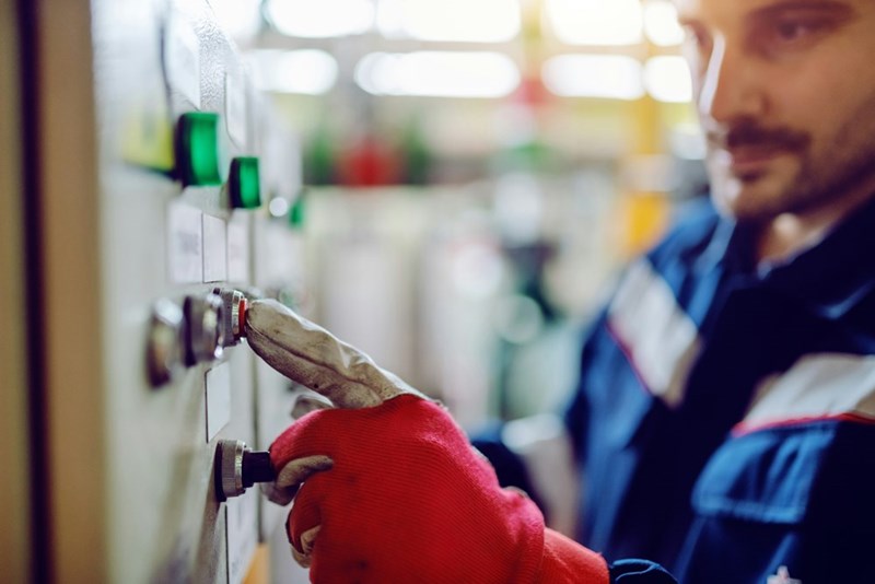 A technician presses a button on a machine while doing repairs.