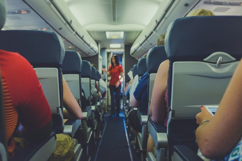Passengers on an airplane looking down the aisle.