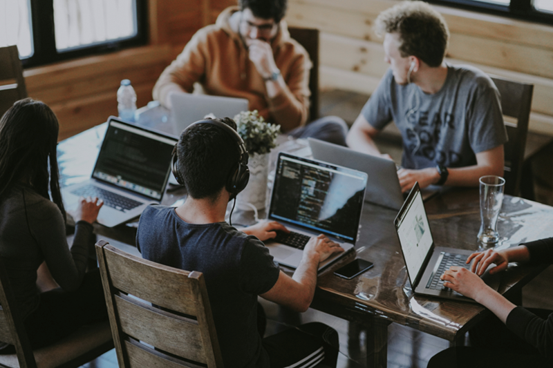 A group of people use laptops around a conference table
